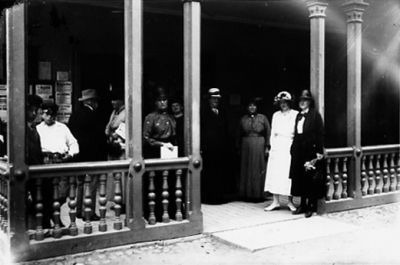 Ett antal personer stående på veranda.
