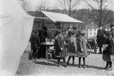 Ett antal personer vid marknadsstånd.
Nyckelord: Kullersten