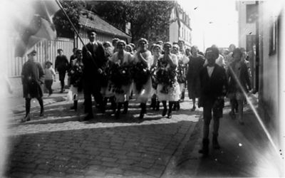 Ett antal personer gående på gata.
Nyckelord: Dräkt