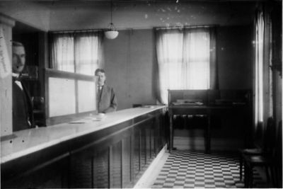 2 män stående bakom en disk i en lokal.
