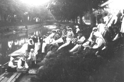 Ett antal personer sittande och stående vid vattendrag.
