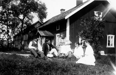 Familj sittande framför byggnad.
