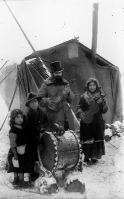 Familj stående framför tält.
Nyckelord: Tält Vinter Trumma