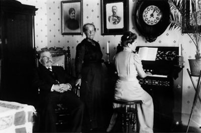 Kvinna sittande vid orgel. Man sittande och kvinna stående bredvid.
Nyckelord: Orgel Klocka