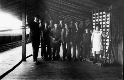 Ett antal personer stående under ett tak.
Nyckelord: Repslageri