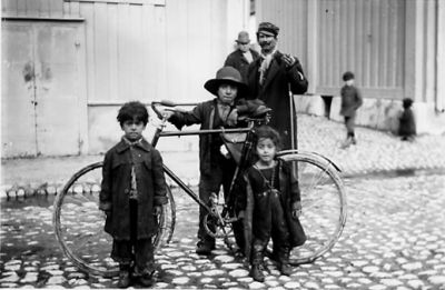 2 män och 4 barn stående med cykel på gata.
Nyckelord: Cykel Käpp Kullersten