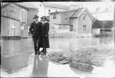 Man och kvinna stående i vatten framför byggnader.
Nyckelord: Översvämning