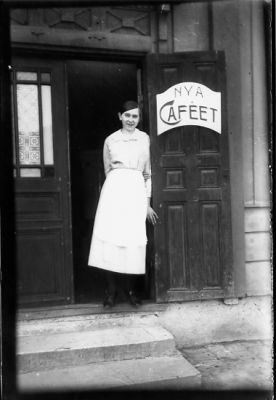 Kvinna stående i dörröppning till café.
