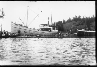 Ett antal personer i vatten, på brygga och på båt.
