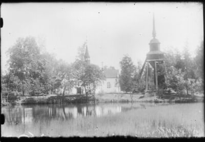 Vattendrag med kyrka och klockstapel i bakgrunden.
Nyckelord: Klockstapel