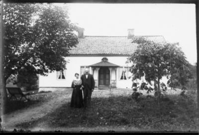 Man och kvinna stående framför byggnad.
Nyckelord: Trädgård