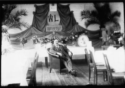 Man sittande i fotölj i matsal.
Nyckelord: Blommor Skylt