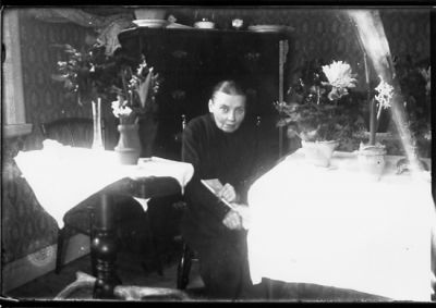 Kvinna sittande vid bord.
Nyckelord: Blommor