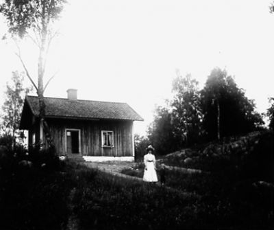 Kvinna och pojke stående framför byggnad.
