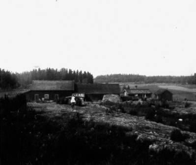 Barn stående framför lantgård.
