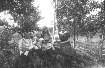 Kvinna, 3 flickor och 1 pojke sittande på berg.
Nyckelord: Skogsbacke