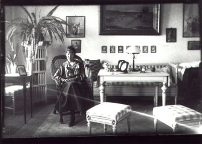 Kvinna sittande i rum.
Nyckelord: Tavla Lampa Pall