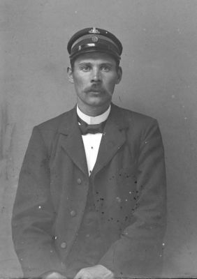 Man med uniformsmössa sittande i rum
Nyckelord: Mössa