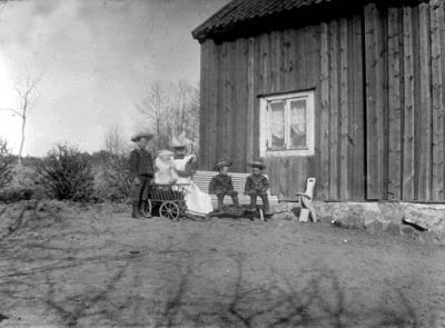 1 kvinna 3 pojkar och 1 flicka framför byggnad
Nyckelord: skrinda barnstol