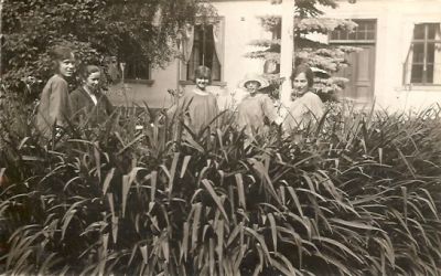 5 kvinnor i trädgård framför hus
