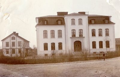 En liten flicka framför en skolbyggnad
