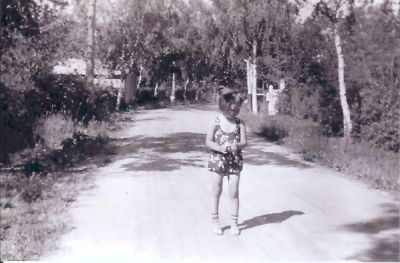 Liten flicka promenerande på grusbelagd gata
