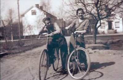 2 flickor stående med cyklar framför byggnader
Nyckelord: Cykel