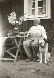 Man och hund sittande vid husvägg
Nyckelord: Hund Blommor