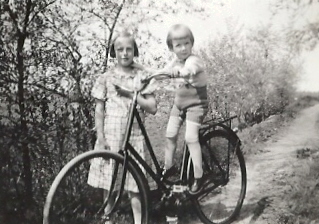 Flicka stående vid pojke som sitter på damcykel
Nyckelord: Cykel