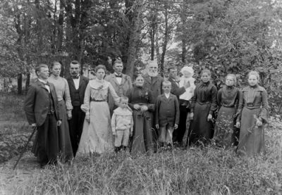 En grupp vuxna och barn stående i naturen
