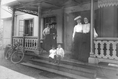 4 kvinnor och 2 barn på veranda
Nyckelord: Cykel Hatt Dräkt Snickarglädje