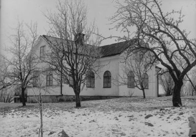 Vitputsad byggnad med stora rundade fönster
