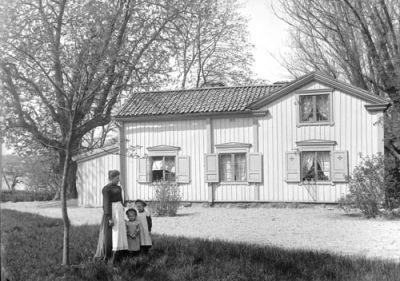 Kvinna och 2 flickor framför byggnad
