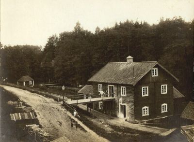 Några personer utanför kvarnbyggnad vid vattendrag
Nyckelord: Kvarn