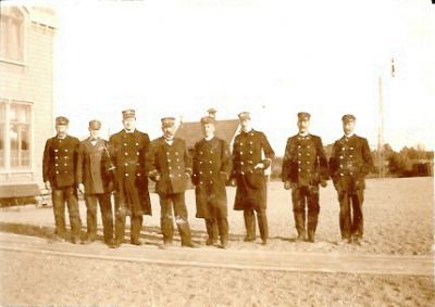 8 stationstjänstemän stående utanför järnvägsstation
Nyckelord: Järnvägsstation Uniform