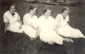 4 ljust klädda kvinnor sittande på gräsmatta
