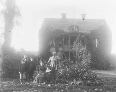 Man kvinna och 4 barn framför hus
Nyckelord: Dräkt