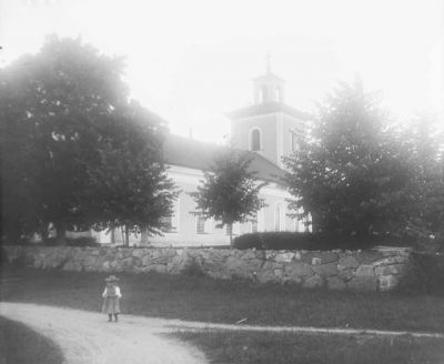 Liten flicka stående på väg intill kyrka
Nyckelord: Kyrka Dräkt