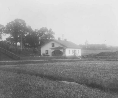 Byggnad på landet med kyrka i bakgrunden
