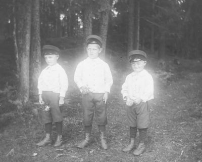 3 små pojkar med skärmmössor stående i skogen
Nyckelord: Dräkt 