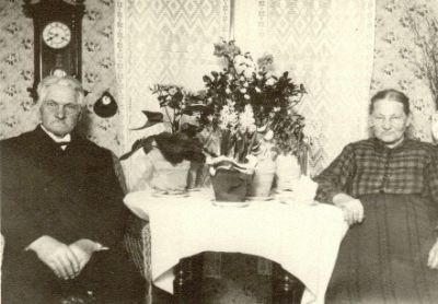 Äldre par sittande vid blomsterfyllt bord
Nyckelord: Dräkt Väggklocka Tapet