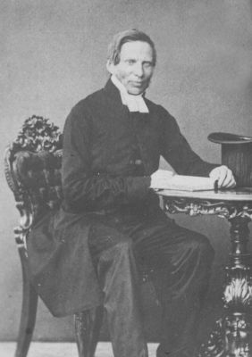 Prästklädd man sittande i rum
