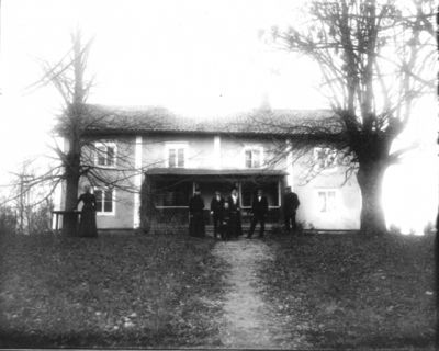 3 män 3 kvinnor 1 barn framför hus
