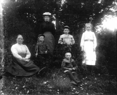 2 kvinnor och 4 barn i skogsbacke
