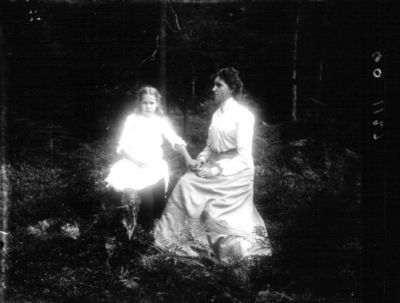 Kvinna och flicka sittande i skog
Nyckelord: Dräkt