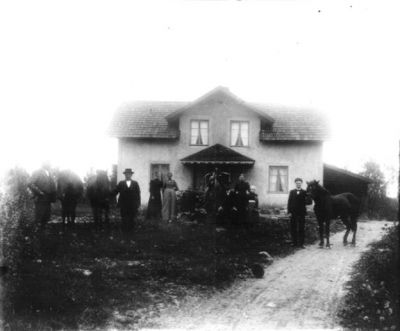 3 män 3 kvinnor 3 hästar och 1 barn framför hus
Nyckelord: Häst Hus
