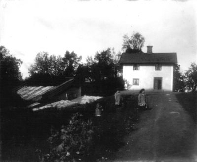 Kvinna och 3 barn framför hus
Nyckelord: Dräkt