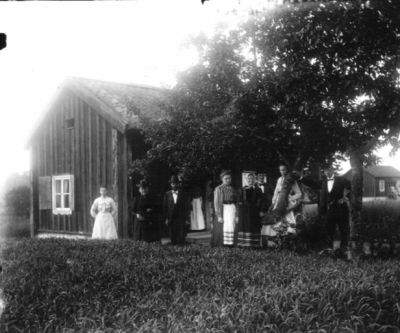 4 män och 4 kvinnor framför hus
Nyckelord: Dräkt
