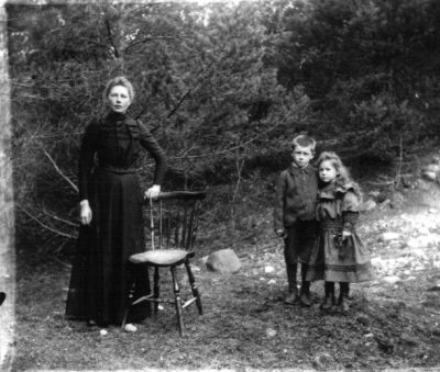 Kvinna pojke och flicka stående vid stol utomhus
Nyckelord: Stol Dräkt