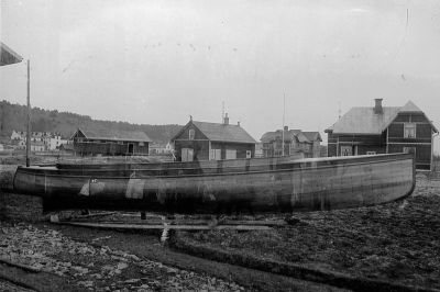 Båt på tomt framför byggnader
Nyckelord: Båt  Byggnad